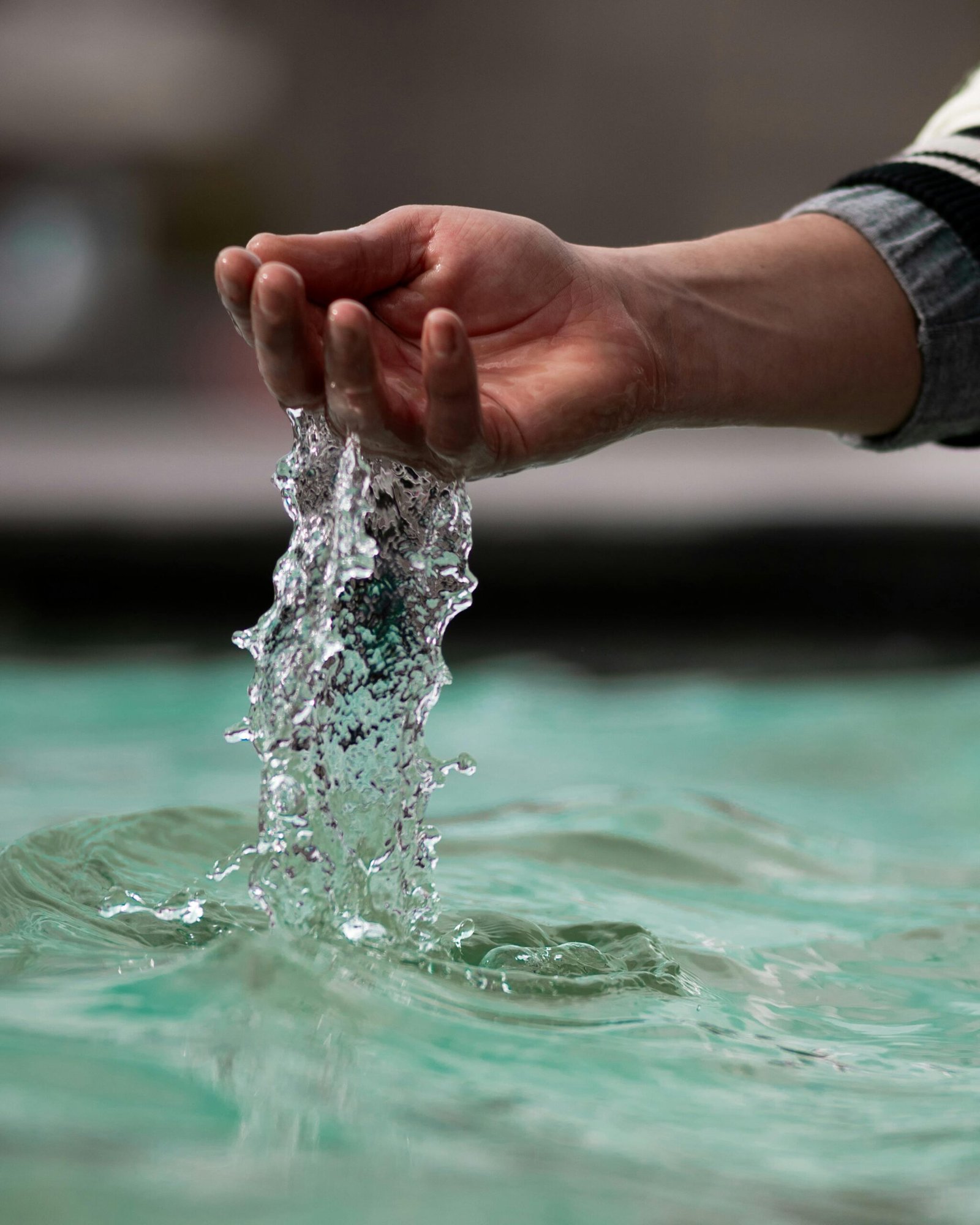 Close-up of a hand pouring water in a fountain in Kayseri, Türkiye, capturing the fluid motion.